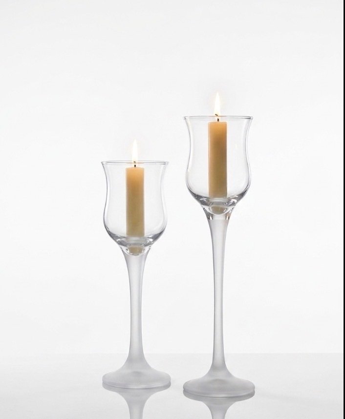 Two vintage cordial glasses with clear tulip bowls and frosted satin stems and bases, displayed with lit pillar candles; taller glass at right.