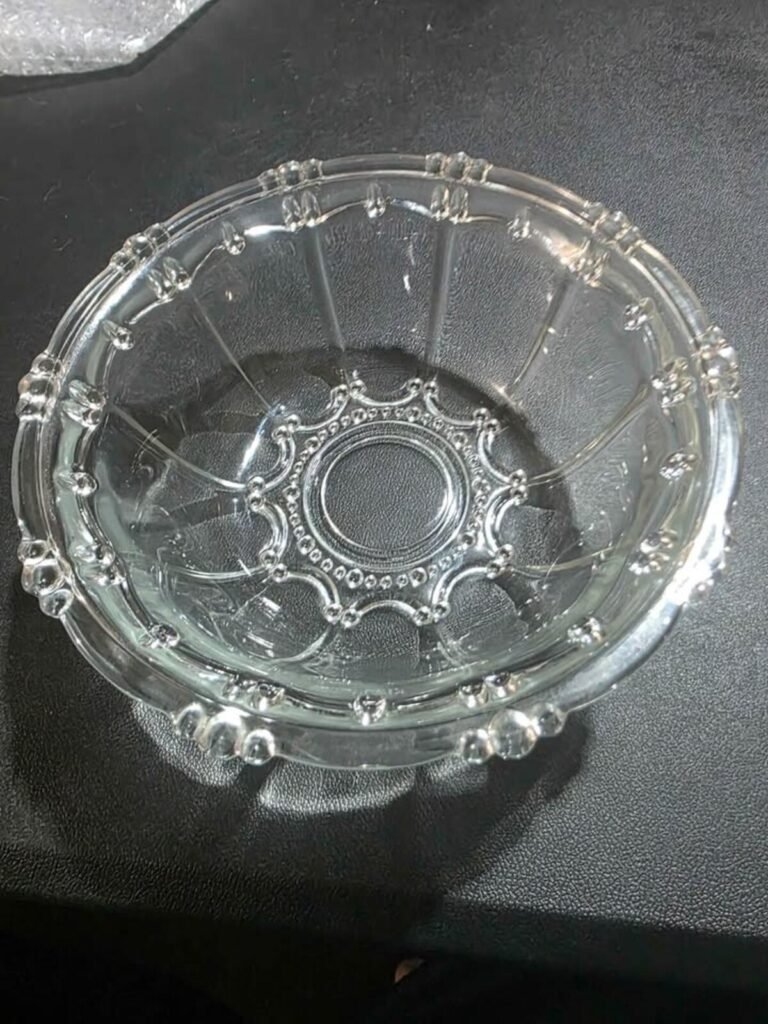 Top view of clear pressed glass bowl with scalloped beaded rim, paneled vertical panels and starburst pattern at the base.