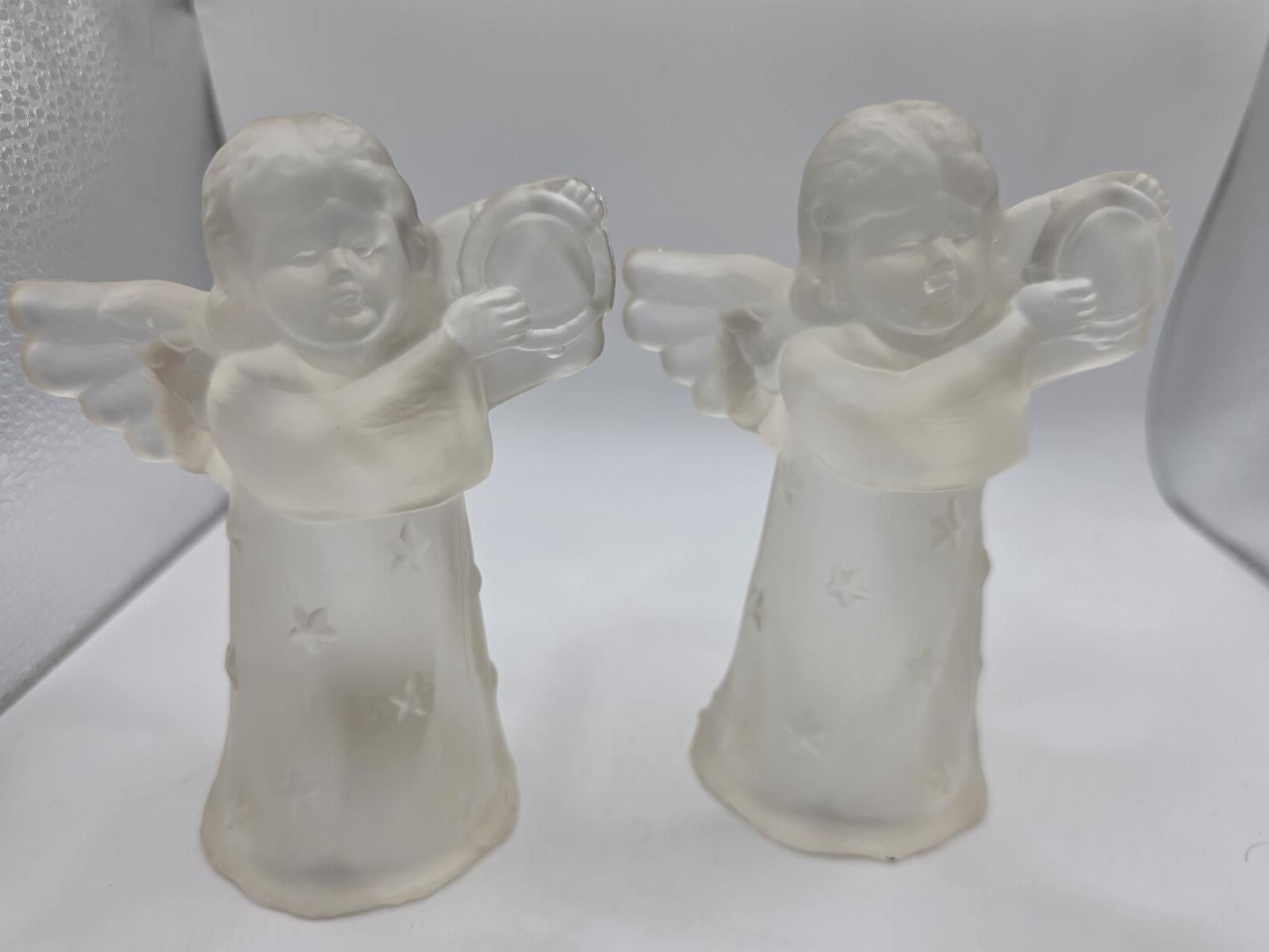 Close-up front view of two frosted glass cherub angels holding round tambourines, showing wings and star-patterned gowns.