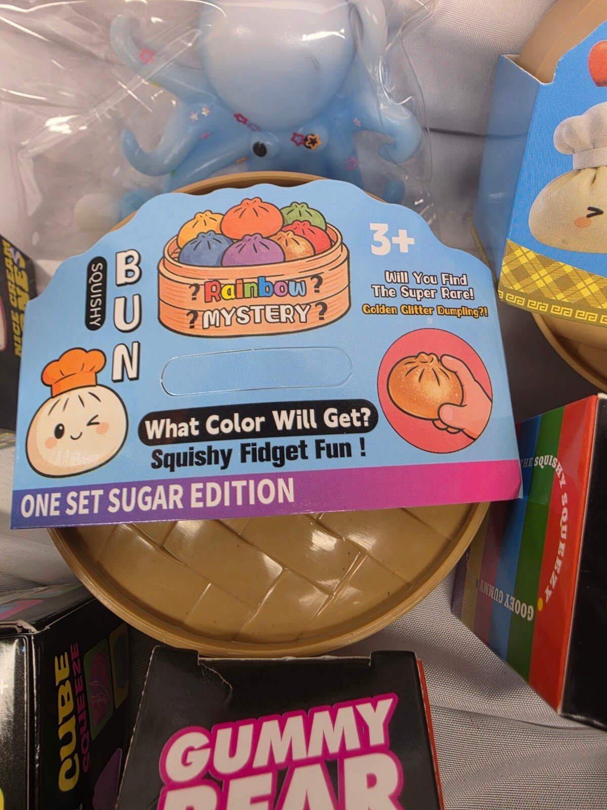 Close-up of packaging backing with 'One Set Sugar Edition' bun graphic and a blue octopus squishy in plastic.