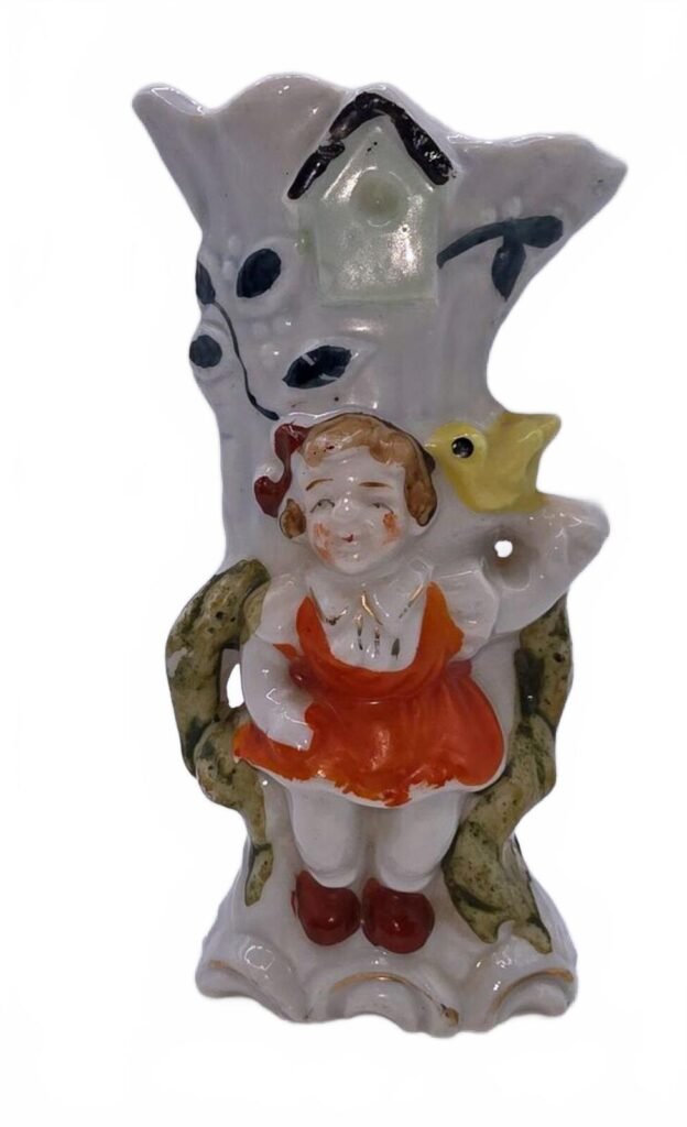 Front view: white porcelain bud vase with figural girl in red pinafore and yellow bird.
