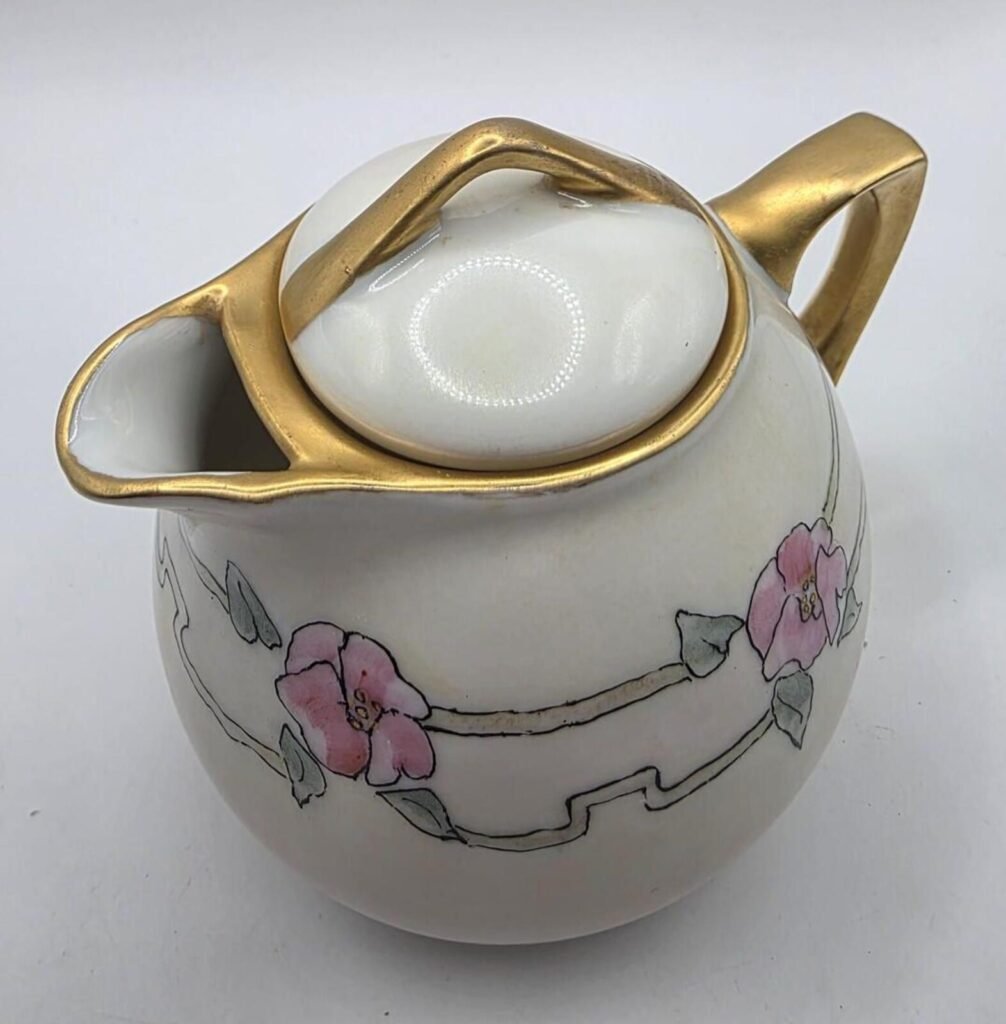 Top-down close view of Epiag Royal creamer with fitted lid, gold-gilt handle and spout, and pink floral decoration.