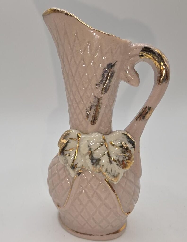 Pink ceramic pitcher bud vase, full view showing raised diamond texture, applied white leaf detail and gold trim.