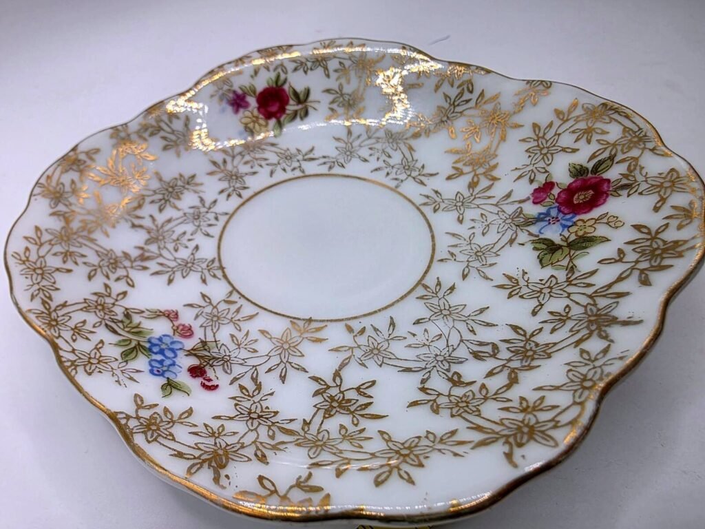 Close-up angled view of Lefton porcelain saucer showing gold floral lattice pattern, colorful hand-painted blossoms and scalloped gilt rim.