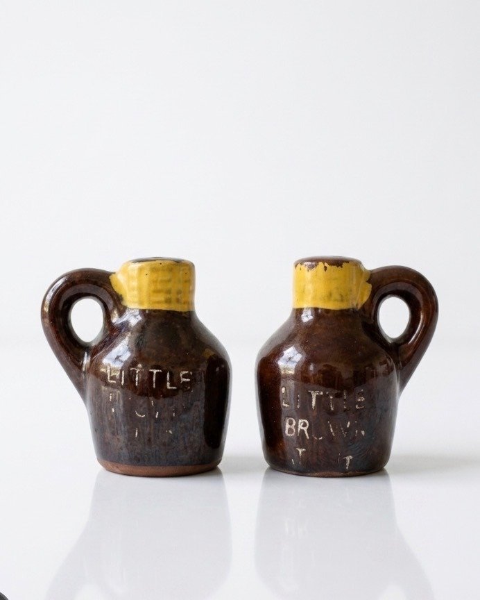 Pair of small brown glazed ceramic jug salt and pepper shakers with yellow neck bands, handles and faded embossed 'Little Brown Jug' lettering