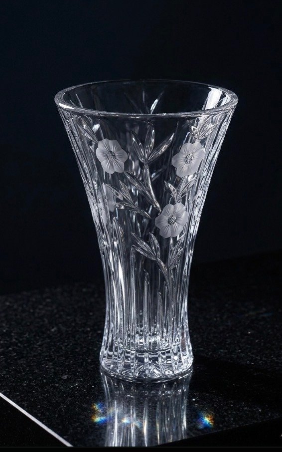 Clear trumpet-shaped crystal vase, frosted floral etching and vertical optic ribbing visible, front three-quarter view.