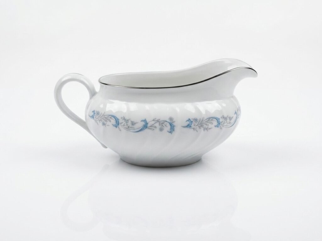 White Camelot China Gracious gravy boat, side profile showing blue floral scroll band and silver-trimmed rim.