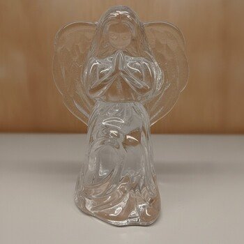 Centered front view of clear crystal angel candle holder showing folded hands, wing texture and robe detailing against a wood backdrop.