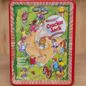 Close frontal view of the Cracker Jack rectangular tin showing the full illustrated baseball scene, visible logo, and red trim.